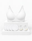 Kit Primeiras Mamadas Arkemis: sutiã de amamentação Jelly Strip branco, almofadas absorventes e protetores de leite sobre pódio.