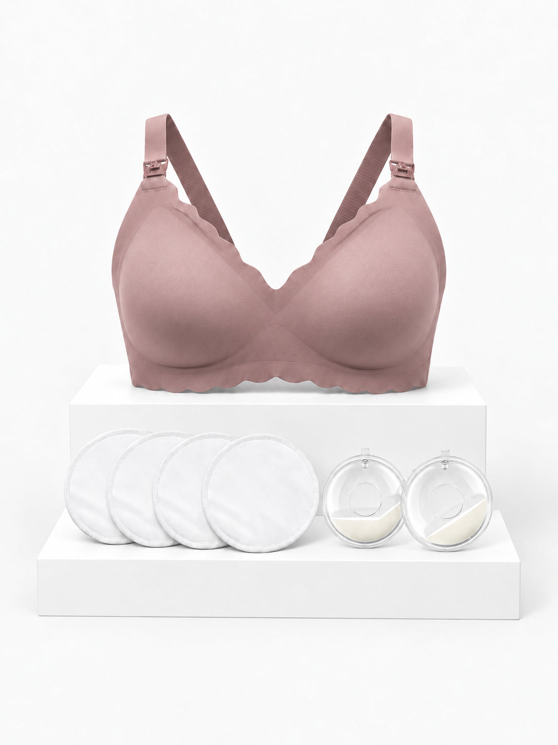 Kit Primeiras Mamadas Arkemis: sutiã de amamentação Jelly Strip rosa, almofadas absorventes e protetores de leite sobre pódio.